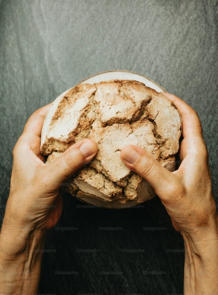 Hands breaking bread at a wooden table