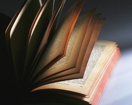 Open old book resting on a wooden table in soft natural window light