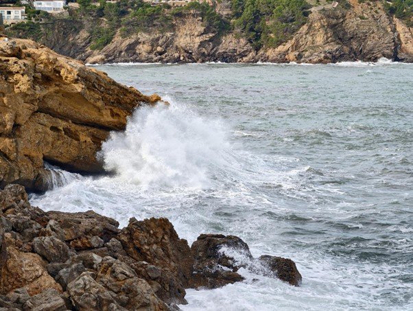 Powerful ocean waves striking rocky coastal cliff.