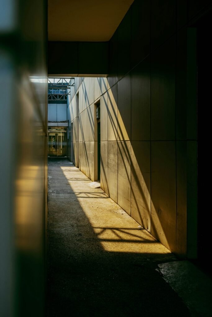 : A narrow path disappearing between shadowed walls