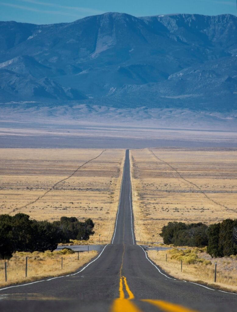 Long paved road stretching through dry open landscape toward the horizon.
