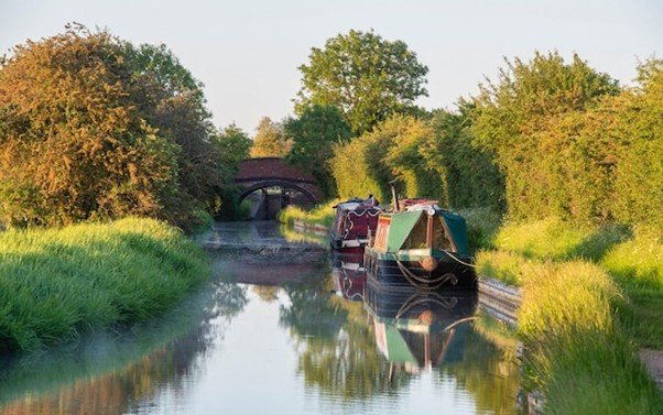 11. The Servant Who Proceeds Canal towpath running alongside calm water with narrowboats.