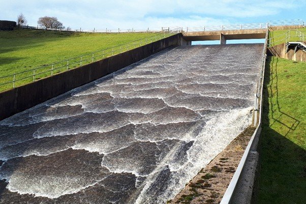 Concrete spillway descending from a reservoir dam.