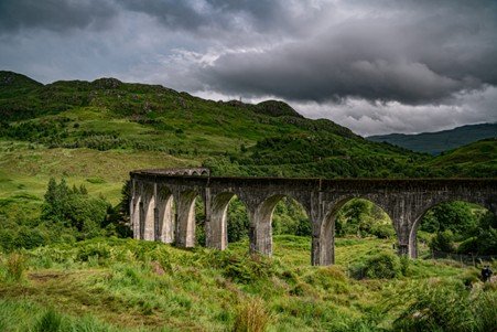Stone railway viaduct with multiple arches spanning a countryside valley.