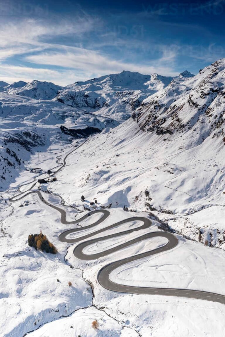A narrow road winding through a snow-covered mountain pass.