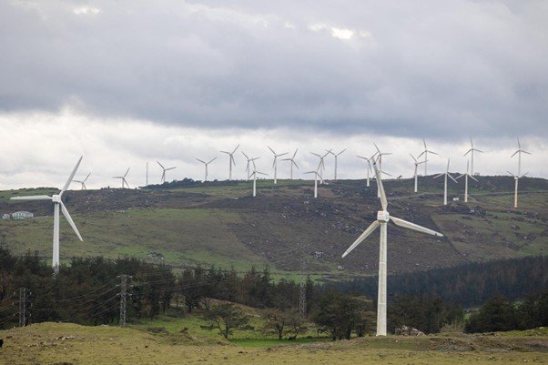 Tall wind turbines standing across a grassy hillside.