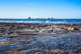 Flat rock shelves extending into the sea along a rugged coastline.