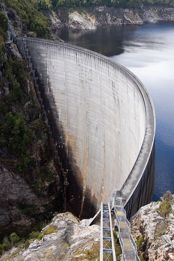 A large reservoir wall holding back water in a rural valley.