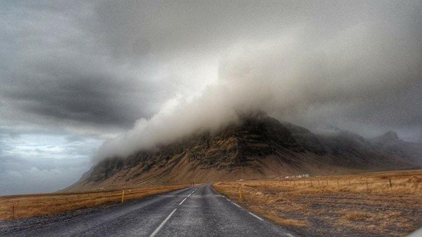 Narrow road winding across steep mountain slopes in a high pass landscape.