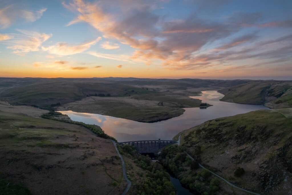 Large reservoir dam holding back a wide body of water.