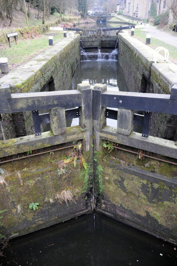 Canal lock chamber with wooden gates and stone walls.